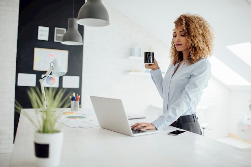 woman at standing desk drinking coffee