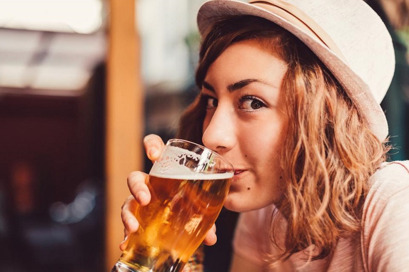 girl taking a sip from a glass of beer