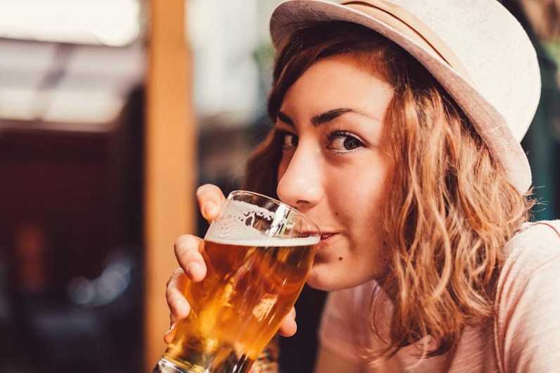 girl taking a sip from a glass of beer