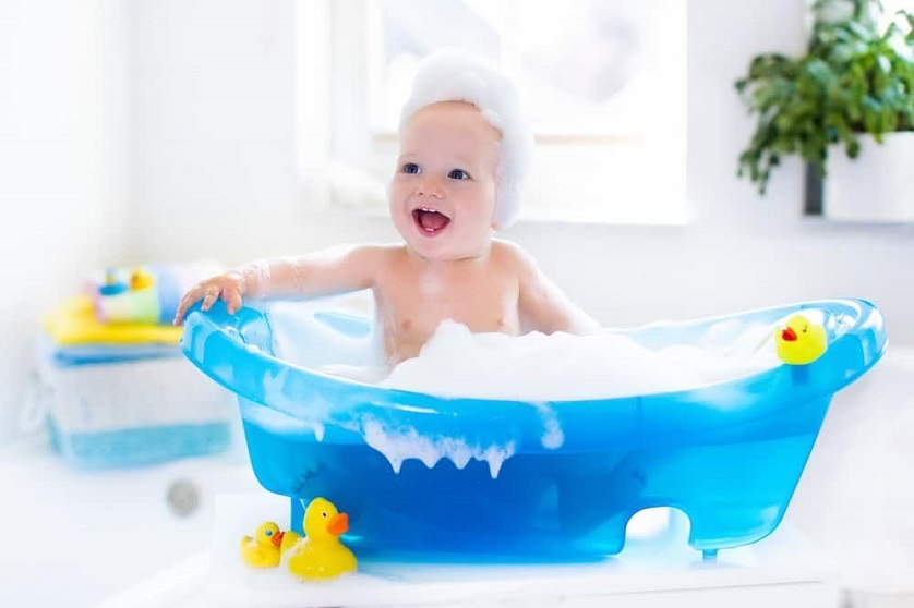 baby taking a bath in a blue bathtub 