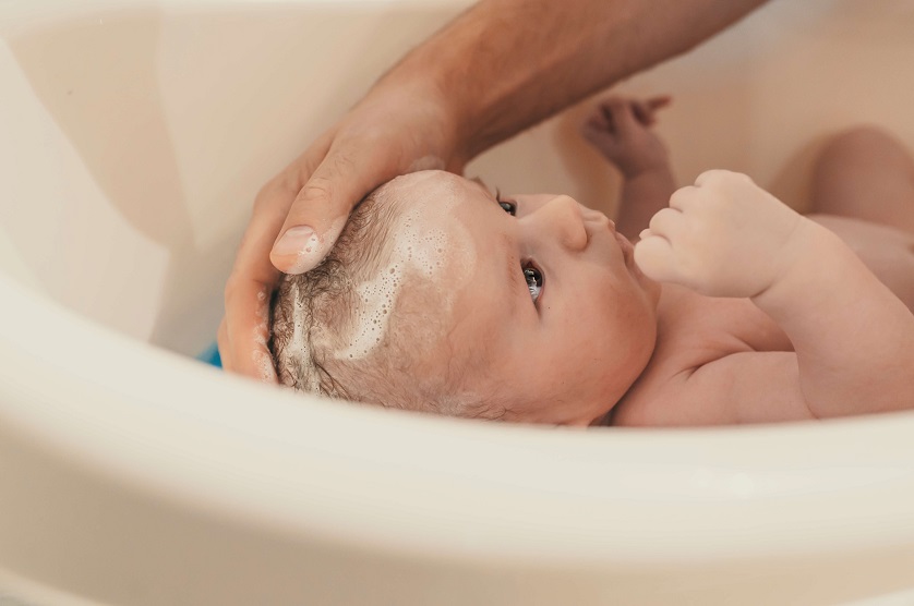 carefully giving a newborn baby a bath  