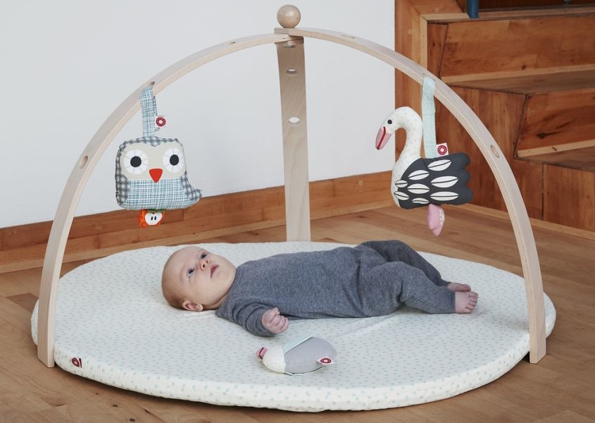 baby on the floor under an activity play gym