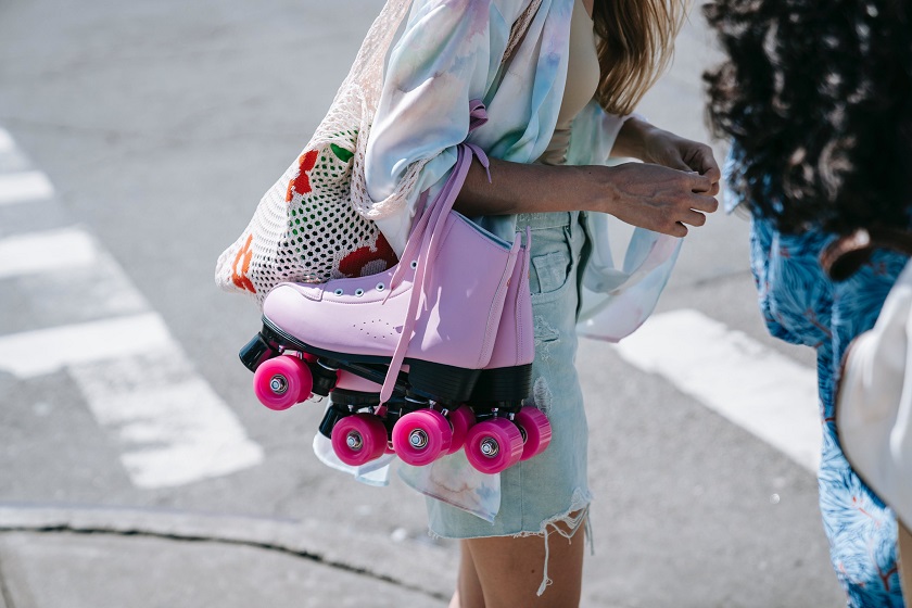 picture of woman standing on a street carrying a bag and a pink roller skates