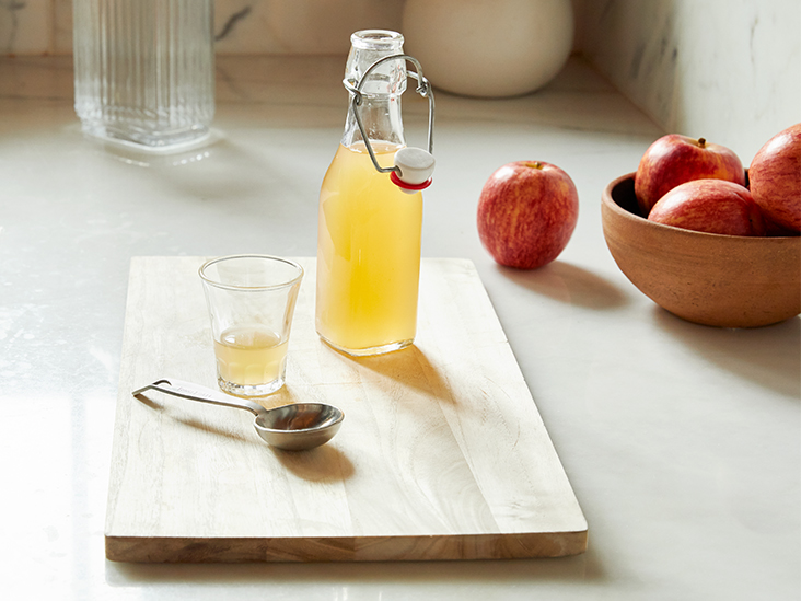 A Bottle of Apple Cider Vinegar with fresh apples behind 