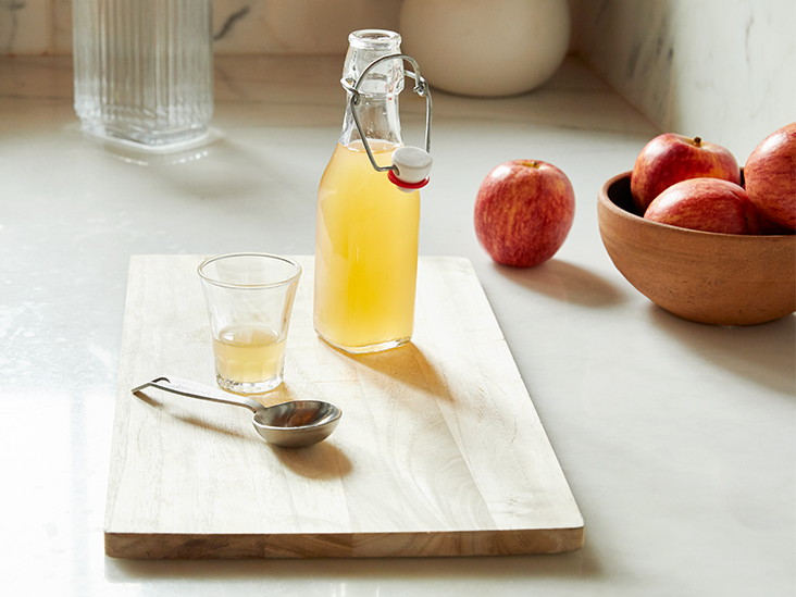 A Bottle of Apple Cider Vinegar with fresh apples behind