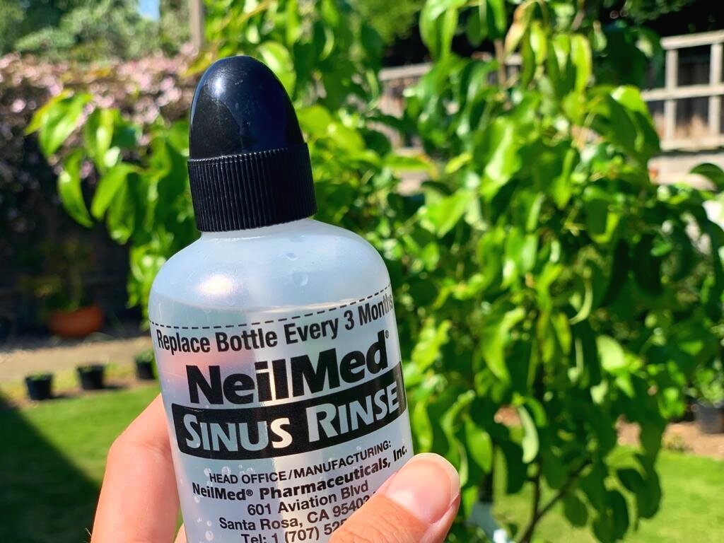 A bottle of Neilmed Sinus Rinse with a tree in the background