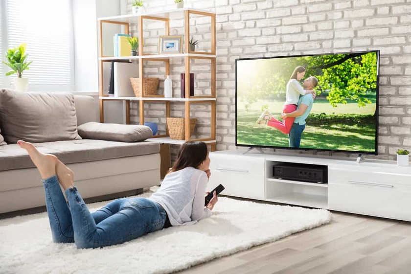 picture of a woman sitting on a livingroom floor on a rug in front a smart tv 32 inch screen 