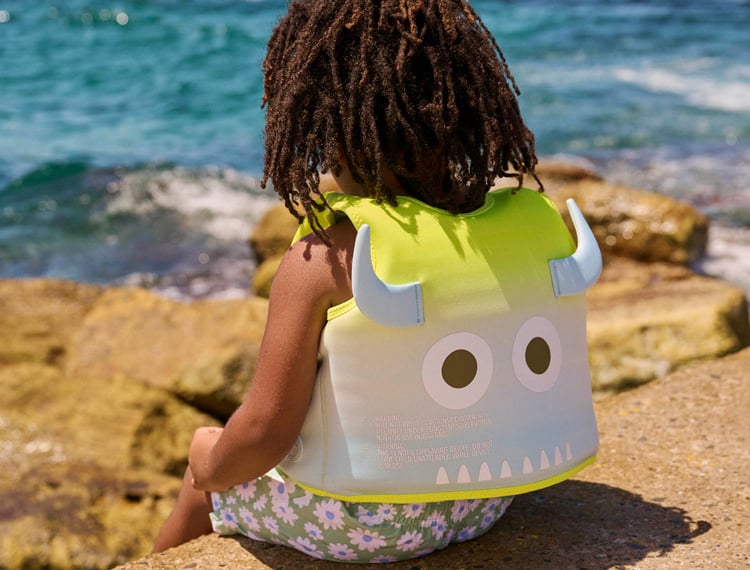 kid by the beach with swimming vests