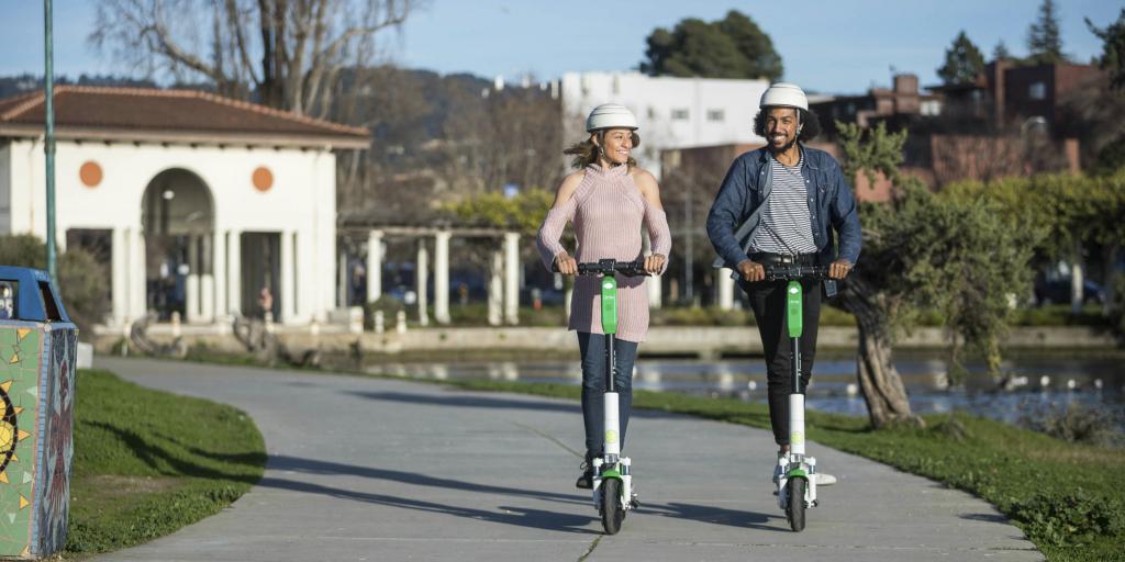 a man and a woman wearing a helmet and riding a scooter
